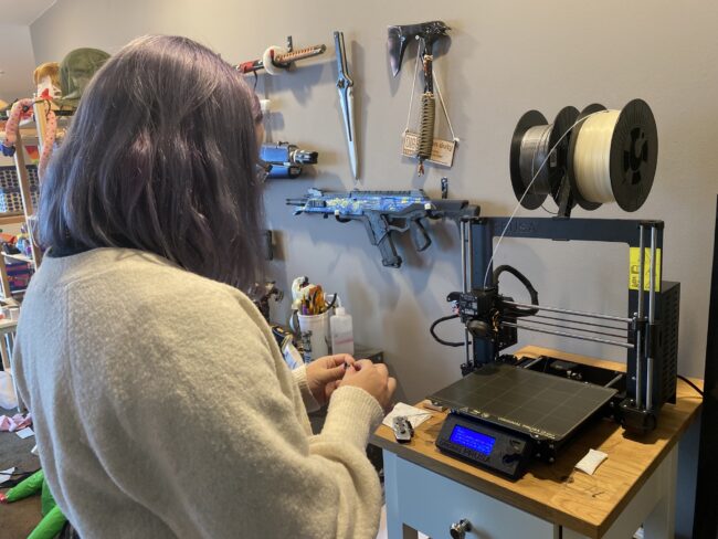 Anna Lorio, cosplayer, prepares to insert her SD card of a 3D modeled Headhunter design into her 3D printer.