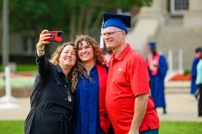 Class of 2023 graduate Jillian Taylor smiles for a selfie on Dallas Hall Lawn. Image courtesy SMU.
