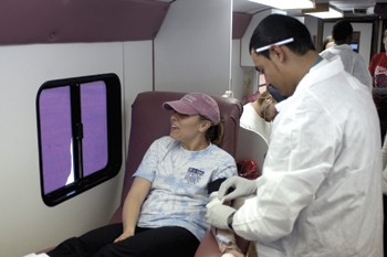 A student braces herself as a doctor prepares to take her blood.