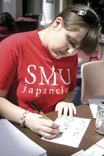 SMU Japan Club member Allison Gab writes out a student's name in Japanese. 