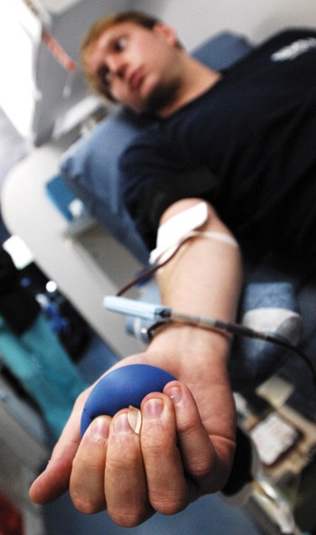 SMU freshman Matt McKenzie squeezes a ball while donating blood at the Bishop Boulevard flagpole.