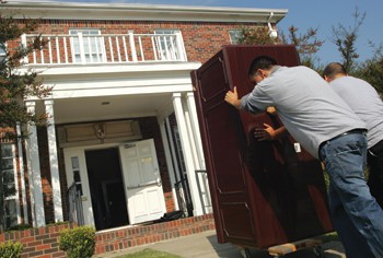 George Gallegos (left) and Marcelo Ochoa (right) roll a desk into the new Residence Life and Student Housing office located in the former Beta Theta Pi Fraternity house on SMU Boulevard.