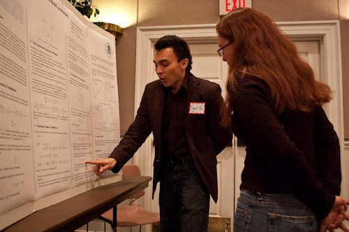 SMU Ph.D. candidate in computational and applied mathematics Michael Uh talking about his research project to a research fair attendee Tuesday afternoon.
