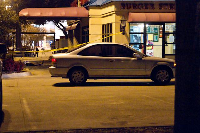 An abandoned car sits in front of the Burger Street fast food restaurant Wednesday evening as the body of one of two victims in a murder crime lies in the drive-thru lane. 