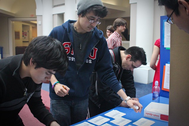 SMU students Oscar Cetina, from left, Samuel Partida, and Robert Hernandez sign letters written in favor of a bill to create a seat for LGBT community members in SMU’s Student Senate.