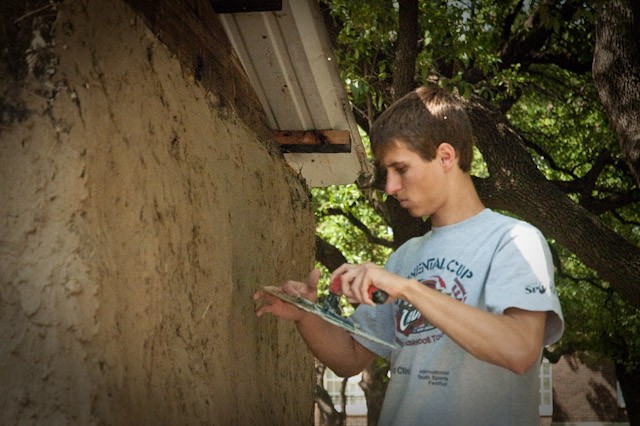 SMU engineering student Joe Nelson helps apply mud to the side of an Ubuntu Blox shelter on display during the Lyle School of Engineering Hunt Institute’s Engineering and Humanity week.