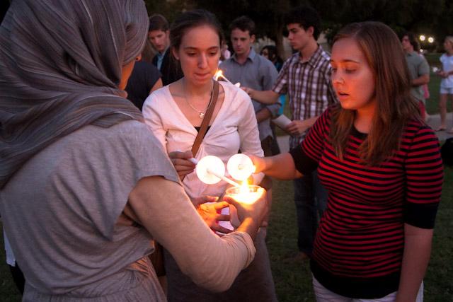 Junior Kiran Jaura, Vice President of the Muslim Student Association, brings a lit candle to junior Natalie Clark and senior Kellie Teague during a brass rendition of “God Bless America,” part of the SMU Service of Remembering. On the steps of Dallas Hall, Sunday evening’s event commemorated the 10th anniversary of 9/11.