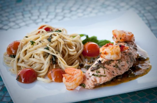 Farnatchi excells in making delicious pasta dishes like this plate of grilled Salmon, shrimp and seasoned linguini.