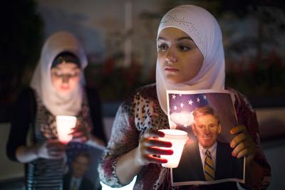 Dilan Samo holds a picture of slain U.S. Ambassador to Libya Christopher Stevens during a candlelight vigil outside the Libyan embassy on Thursday.