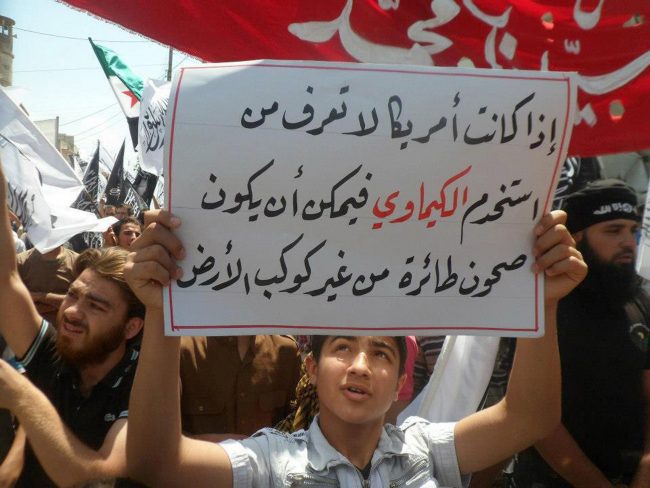 An anti-Syrian regime protester holds up an Arabic sign reading