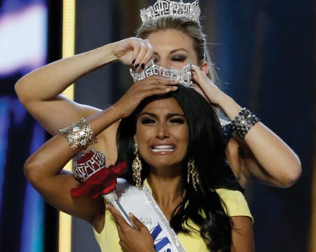 Miss New York Nina Davuluri, front, is crowned as Miss America 2014 by Miss America 2013 Mallory Hagan, Sunday, Sept. 15, 2013, in Atlantic City, N.J. (AP Photo/Julio Cortez)