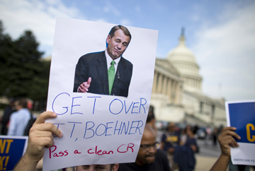 A protestor holds a sign calling on House Speaker John Boehner to pass a clean continuing budget resolution during an event on Capitol Hill in Washington, Friday, Oct. 4, 2013, with the Democratic Progressive Caucus and furloughed federal employees blaming House Republicans on the government shutdown. (AP Photo/ Evan Vucci)
