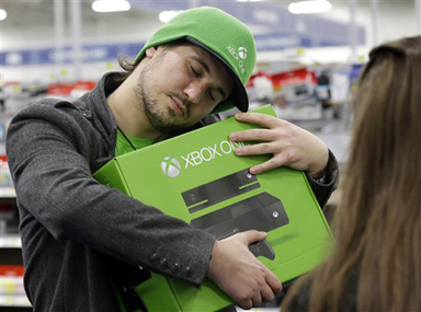 Emanuel Jumatate, from Chicago, hugs his new Xbox One after he purchased it at a Best Buy on Friday, Nov. 22, 2013, in Evanston, Ill. Microsoft is billing the Xbox One, which includes an updated Kinect motion sensor, as an all-in-one entertainment system rather than just a gaming console. (AP Photo/Nam Y. Huh)