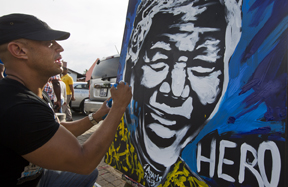 South African artist John Adams, who says he feels driven to paint Nelson Mandela in return for opening up the educational opportunities that enabled him to become an artist, works on a speed-painting of Mandela in the street outside Mandelas old house in Soweto, Johannesburg, South Africa, Saturday, Dec. 7, 2013. South Africa is readying itself for the arrival of a flood of world leaders for the memorial service and funeral of Nelson Mandela as thousands of mourners continued to flock to sites around the country Saturday to pay homage to the freedom struggle icon. (AP Photo/Ben Curtis)