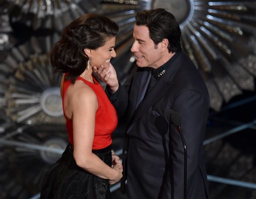 John Travolta, right, touches the face of Idina Menzel as they present the award for best original song at the Oscars on Sunday, Feb. 22, 2015, at the Dolby Theatre in Los Angeles. (Photo by John Shearer/Invision/AP)