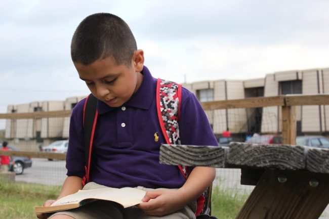 Michael Guevara reads a book outside of "Kids Club." Photo credit: Mary Sanford McClure