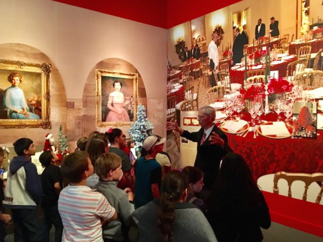 A docent at the George W. Bush Presidential Library and Museum guides a visiting elementary  class through the new Christmas exhibit. Photo credit: Klara Bradshaw