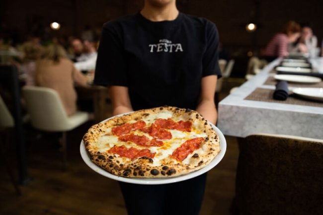 Waitress holds a freshly made pizza at Pizzeria Testa in Dallas. Photo courtesy of Rebecca Reap. Photo credit: Rebecaa Reap