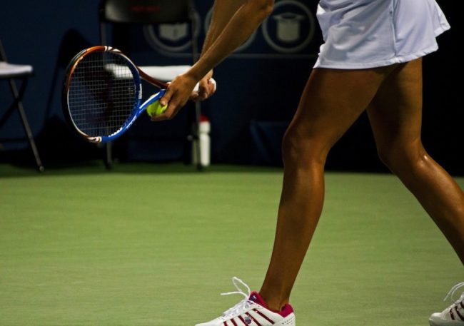 A player about to serve the ball with a Wilson Tennis racket in hand. Photo credit: Creative Commons
