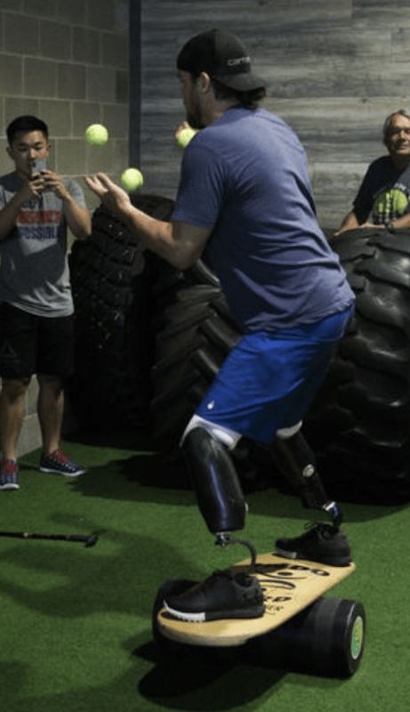 adaptive athlete balances and juggles on balance board. .png