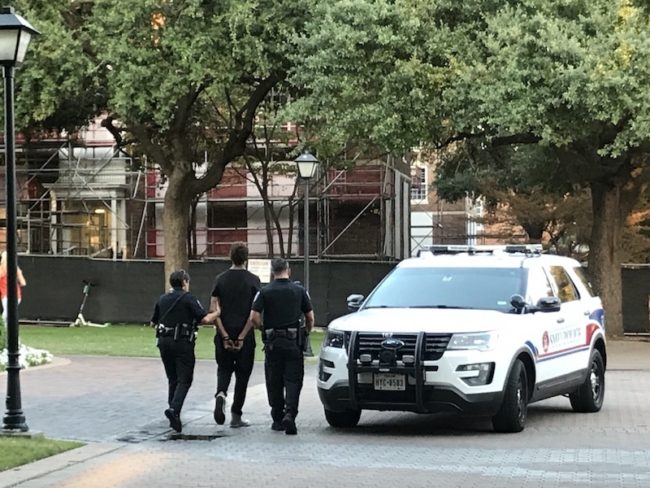 Two SMU police officers escort an arrested suspect to a police car. Photo credit: Michelle Aslam