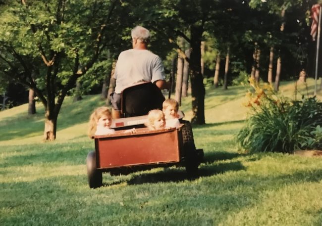 Caitlin Williamson riding behind her grandfathers lawnmower. Photo credit: Caitlin Williamson