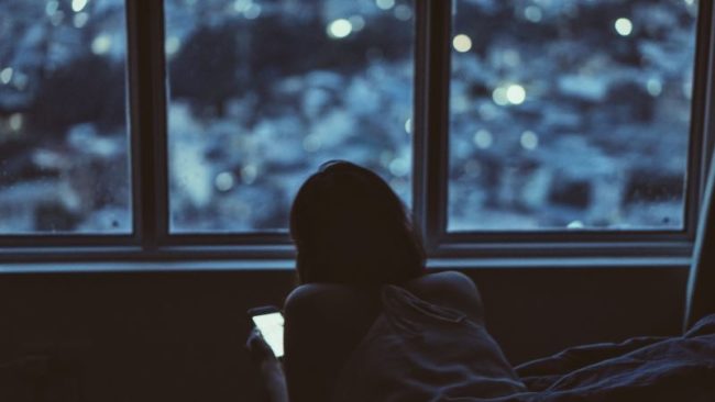 A woman looking out her window, away from her device