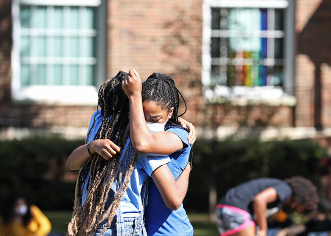 Event participants embrace on Dallas Hall Lawn. The Friday gathering was intended to be a restorative space, and with a call to action for the more disruptive protest to be held Saturday before the Family Weekend home opener football game. Photo credit: Ash Thye