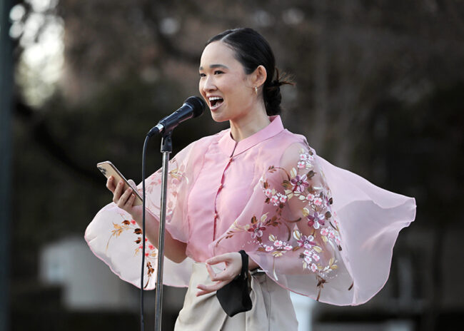 Averie Bishop wearing traditional clothing speaking on Dallas Hall Lawn about AAPI discrimination and violence at Asian Council's vigil on Friday.