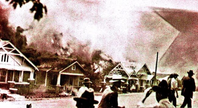 A mob of white rioters burn houses in Tulsa in 1921