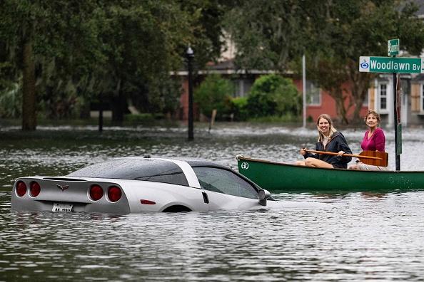People paddle by in a canoe next to a submerged Chevy Corvette in the aftermath of Hurricane Ian in Orlando, Florida on September 29, 2022. - Hurricane Ian left much of coastal southwest Florida in darkness early on Thursday, bringing catastrophic flooding that left officials readying a huge emergency response to a storm of rare intensity. The National Hurricane Center said the eye of the extremely dangerous hurricane made landfall just after 3:00 pm (1900 GMT) on the barrier island of Cayo Costa, west of the city of Fort Myers. (Photo by Jim WATSON / AFP) (Photo by JIM WATSON/AFP via Getty Images)