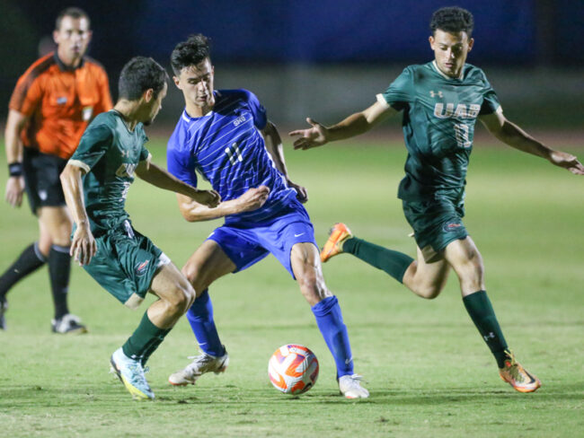 Midfielder Harvey Castro fights to keep the ball against two opposing players.