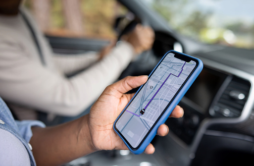 Close-up on an African American couple using the GPS on a cell phone while driving a car - lifestyle concept. **DESIGN ON SCREEN WAS MADE FROM SCRATCH BY US** Photo credit: Getty Images
