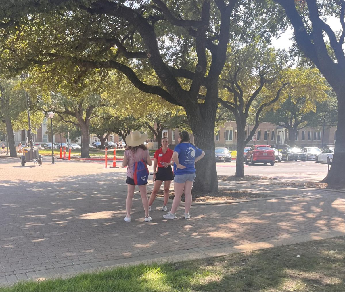 An SMU student chats near Dallas Hall Lawn wearing a red polo.