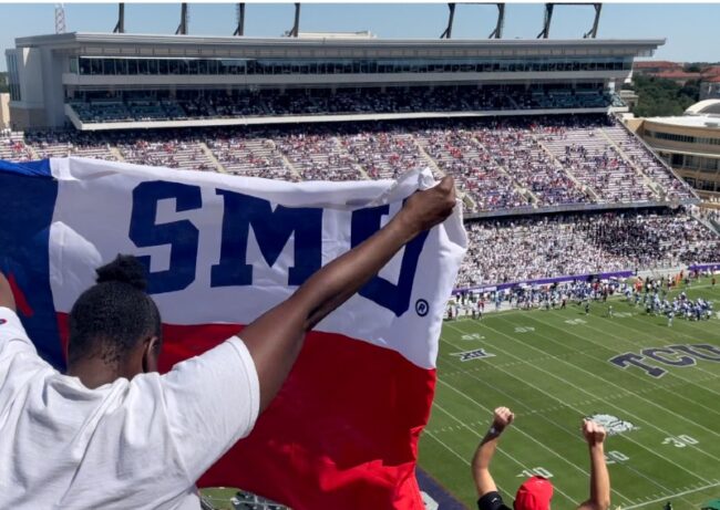 An SMU fan poses with a flag to celebrate the schools victory over TCU at the 2021 Iron Skillet game in Fort Worth. 
