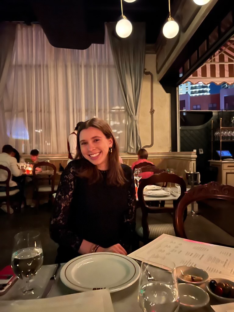 Wallace smiles while seated at a restaurant table. 