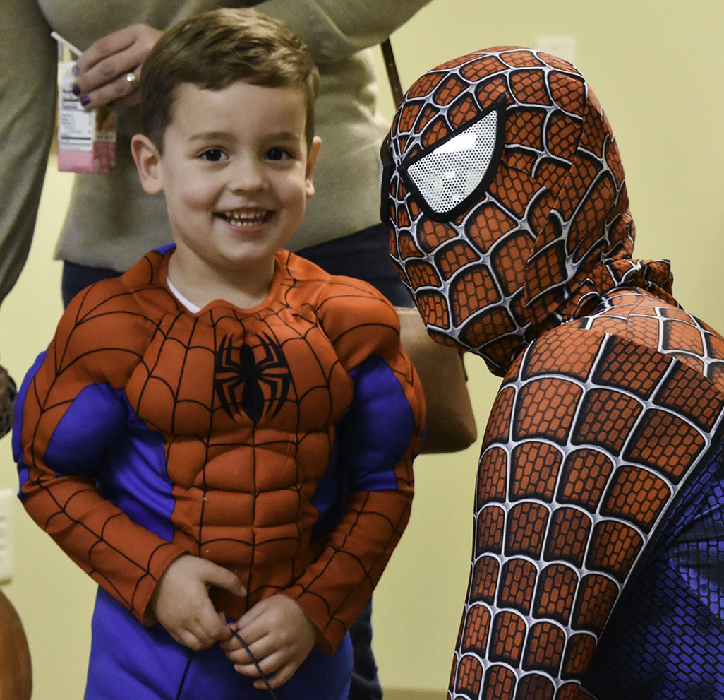 A young boy lights up with excitement after meeting a life sized Spider Man.