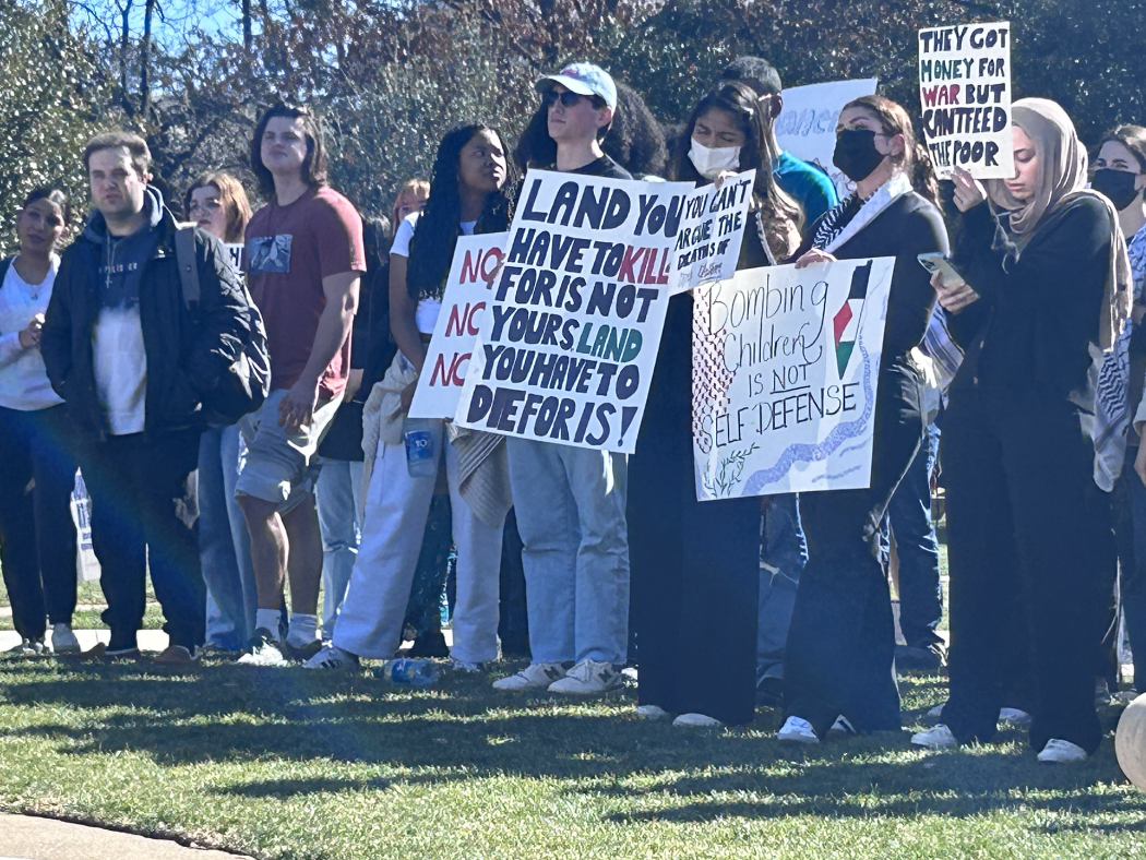 Students gather with signs at a walkout on Dallas Hall lawn.