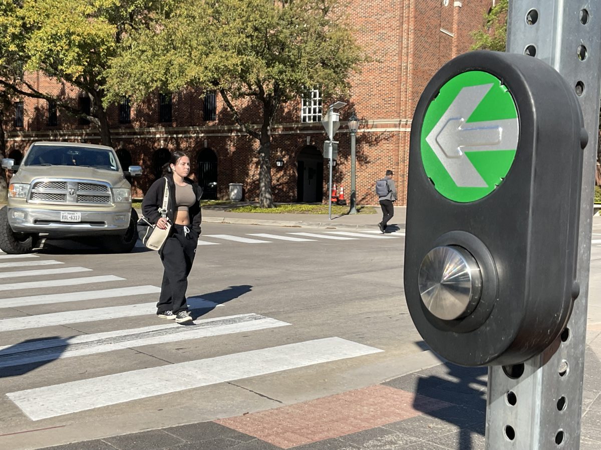 SMU students walk across the intersection of Binkley Avenue and Airline Road with the aid of the new traffic sign.