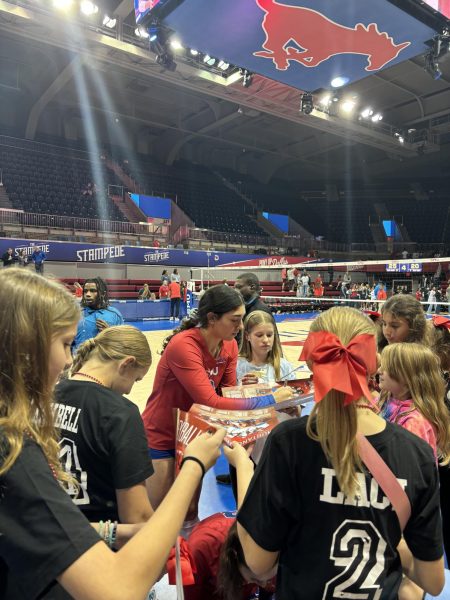 Little girls ask for signed autographs from SMU volleyball team members.