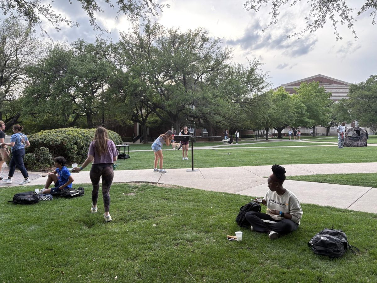 Student aiming a long range gun on Dallas Hall Lawn.
